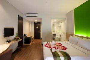 a hotel room with a bed and a green wall at Grand Whiz Hotel Nusa Dua Bali in Nusa Dua
