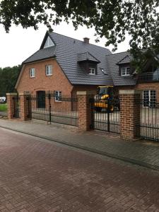 une maison avec une clôture et un camion jaune devant elle dans l'établissement Ferienwohnung Boskop, à Stade