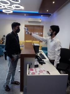 two men wearing masks standing next to a desk at Daffodil Delight - Manyata Tech Park in Bangalore