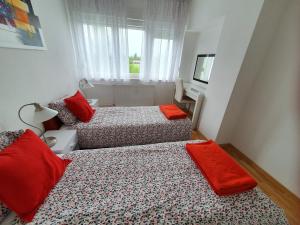 a bedroom with two beds with red pillows and a window at Apartment Rose in Zagreb