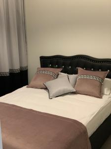 a bed with a black headboard and some pillows at Apartament Jantarowe Zacisze Green in Jantar