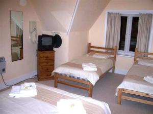 1 dormitorio con 2 camas y un tocador con TV en Kingsley Hotel, en Bournemouth