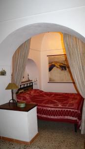 a bedroom with a red bed and a table at Dammusi di Venere - U Locu in Pantelleria
