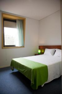 um quarto com uma cama com um cobertor verde em Hotel Comércio em Resende