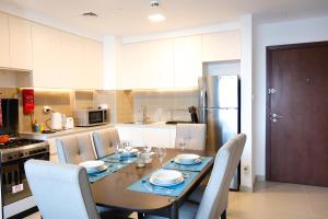 a kitchen with a table with chairs and a refrigerator at SHH - 1BR Apartment in Hayat Boulevard, Townsquare in Dubai