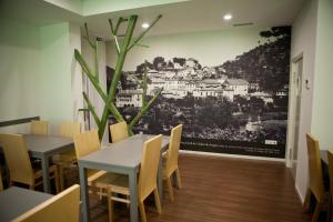 una sala da pranzo con tavoli e sedie e un dipinto sul muro di Hotel Comércio a Resende