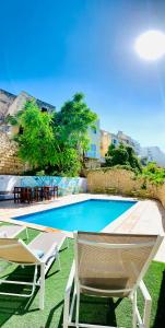 a swimming pool with two lounge chairs and a table at Inhawi Boutique Hostel in St. Julianʼs