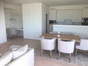 a living room with a wooden table and white chairs at Oostduinkerke Long Island in Koksijde