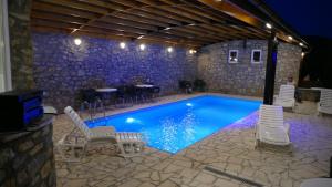 a swimming pool with white chairs and a table at Kuća za odmor "Karalic" in Ležimir