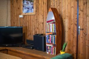 a room with a tv and a book shelf with books at Hostel Paradiso in Tolmin