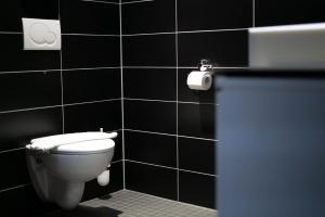a bathroom with a toilet and a black tiled wall at Hotel Wirtshaus Garbe in Stuttgart