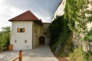 a white building with a brown roof next to a wall at Rooms & Apartments Podsreda Castle in Podsreda