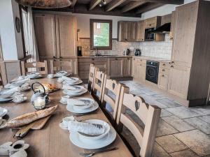 een keuken met een lange houten tafel met stoelen en apparatuur bij Le Cairn in Peisey-Nancroix