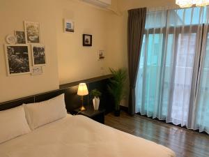 a bedroom with a white bed and a large window at Puli Station Homestay in Puli