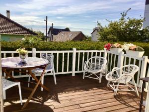 une terrasse en bois avec une table, des chaises et une clôture dans l'établissement Villa Côte-Fleurie, à Trouville-sur-Mer