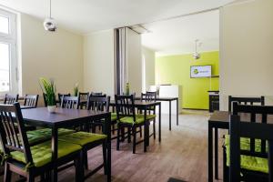 a dining room with tables and chairs and green walls at Clubhostel Dessau in Dessau