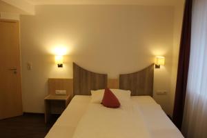 Schlafzimmer mit einem großen weißen Bett und einem roten Kissen in der Unterkunft Hotel-Gasthaus-Kraft in Schauenburg