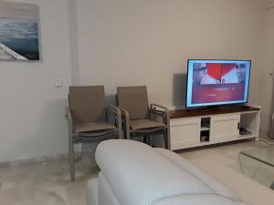 ein Wohnzimmer mit einem Sofa, Stühlen und einem TV in der Unterkunft Balcones del Chaparral in Mijas , Costa des sol . in Mijas Costa