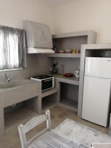 La cuisine est équipée d'un réfrigérateur blanc et d'un évier. dans l'établissement Sahara Apartments, à Kastraki Naxou