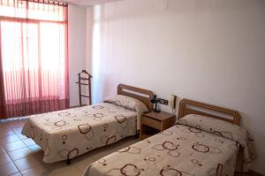 sypialnia z 2 łóżkami i oknem w obiekcie Hostal Fontdemora w mieście Mora la Nueva