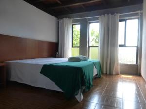 a bedroom with a bed with green sheets and windows at Campismo Rural Vale dos Moinhos Gerês in Geres