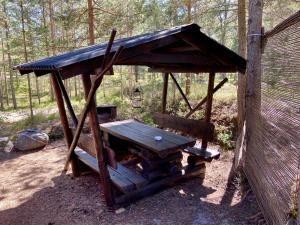 a picnic shelter with a picnic table in the woods at Nõva Madise Guesthouse in Rannaküla