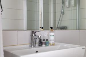 un lavandino in bagno con 2 bottiglie di sapone e uno specchio di Bryggan Fjällbacka a Fjällbacka