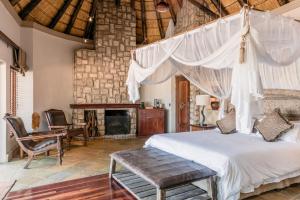 een slaapkamer met een hemelbed en een open haard bij Shumbalala Game Lodge in wildreservaat Thornybush +72 foto's