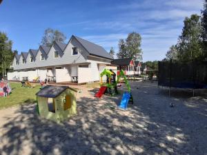 um parque infantil com equipamento de brincar em frente a uma casa em Domki u Leona em Dąbki