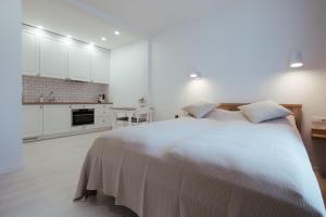 a white bedroom with a large bed and a kitchen at Pas Aldona in Palanga