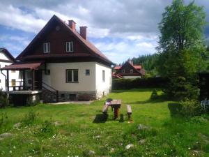 a house in a field with a yard with a bench at Villa Ester in Tatranská Lomnica