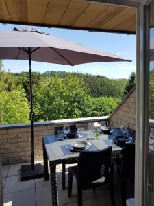 a patio with two tables and an umbrella at TERRASSES DE MALMEDY DUPLEX LE BONHEUR DES ARDENNES - 432 - With Airco in Malmedy