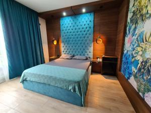 a bedroom with a bed with a blue headboard at Hotel Zeleni Vir in Niš