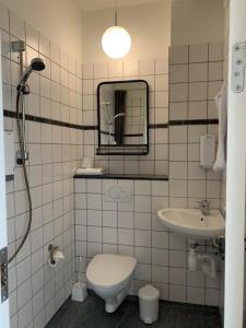 a bathroom with a toilet, sink and mirror at Den Gamle Arrest in Ribe