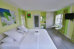 duże białe łóżko w pokoju z zielonymi ścianami w obiekcie Bunny Hill Resort w mieście Chon Buri