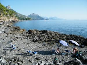 people sitting on top of a sandy beach at Hotel Villa Delle Meraviglie in Maratea