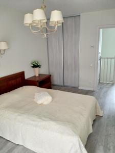 ein Schlafzimmer mit einem weißen Bett und einem Kronleuchter in der Unterkunft Baltieji apartamentai in Palanga