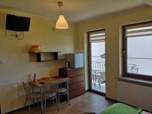 a small kitchen with a table and chairs and a balcony at Rivabell in Ostrowo