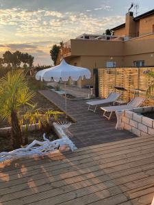 a wooden deck with a white umbrella and benches at Cupido da Simona in Ostellato