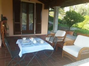 een patio met een tafel en stoelen op een veranda bij Casa Intignano - Camera con bagno e portico vista lago in Tremezzo