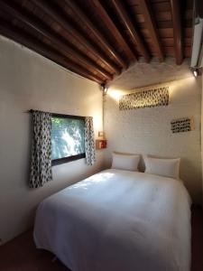 Un dormitorio con una gran cama blanca y una ventana en Dear B&B en Anping