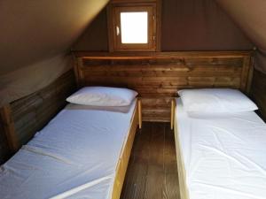 two beds in a small room with a window at Càmping Rural Montori in Ultramort
