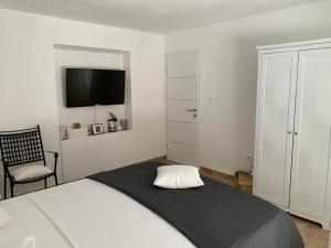 a white bedroom with a bed and a chair at House Damić in Korčula +26 photos