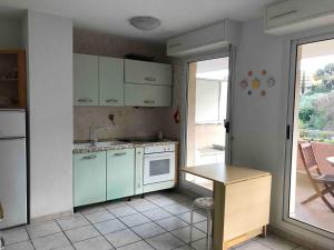 a kitchen with blue cabinets and a table and a window at Sun&Sea Terrace Two-Bedroom Apartment in Roquebrune-Cap-Martin