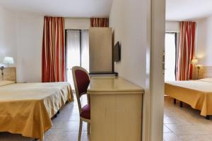 una camera d'albergo con 2 letti e una scrivania con sedia di Hotel Avana Mare a Rimini