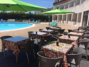 een groep tafels en parasols naast een zwembad bij Hotel Meia Lua in Ovar