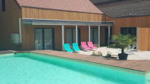 a swimming pool with chairs next to a house at Au Petit Pressoir B&B in Givry