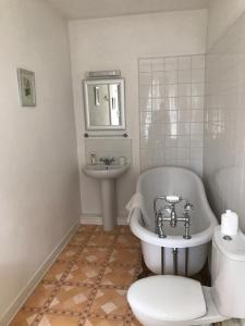een badkamer met een bad, een wastafel en een toilet bij Chambres d'Hôtes Belle Vallee in Domfront