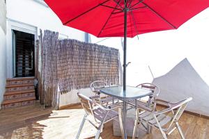 a table and chairs with a red umbrella on a patio at Acogedor Dúplex con terraza privada en la playa in Valencia