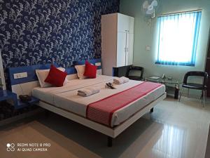 a bedroom with a large bed with red pillows at Hotel BluRay in Belgaum
